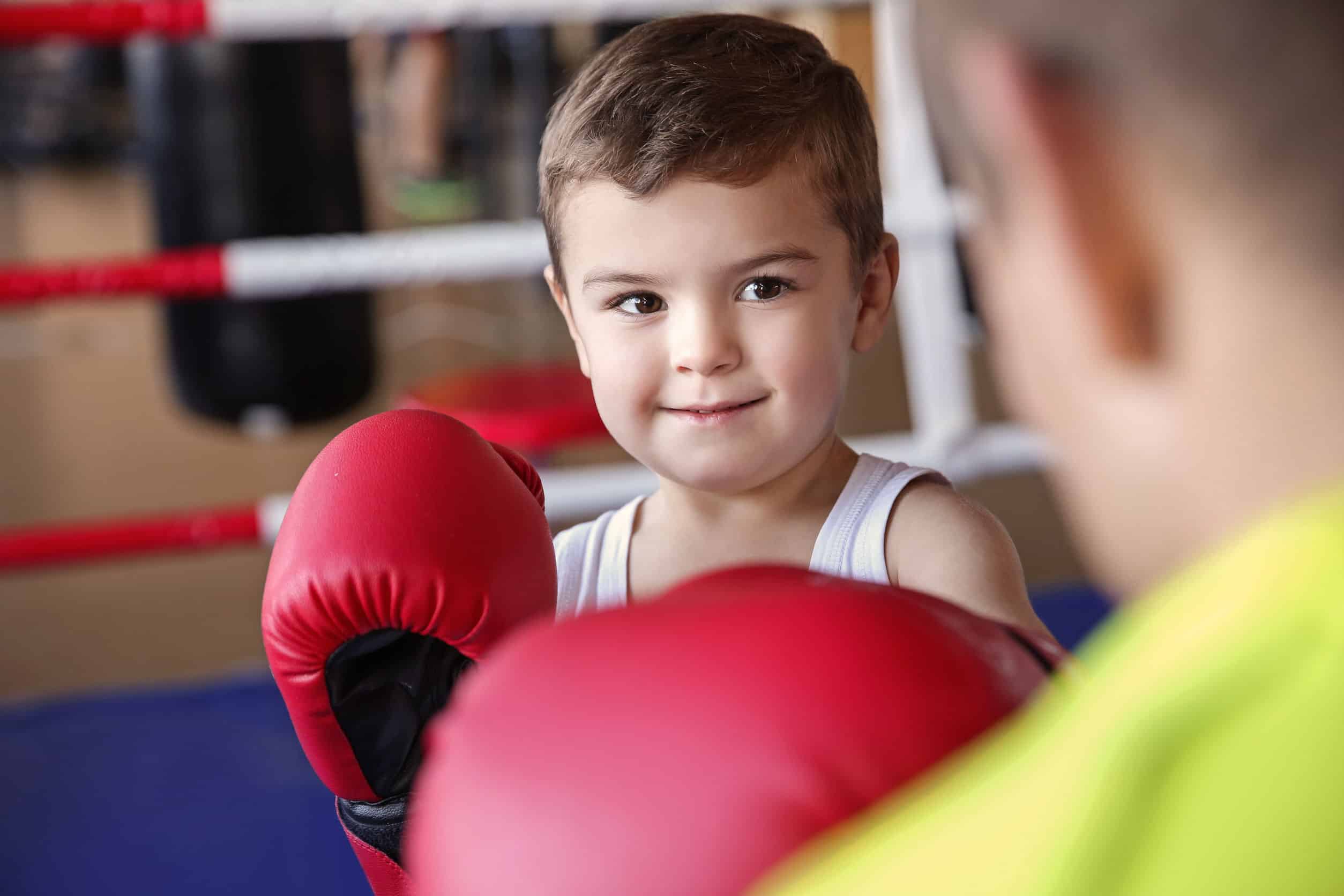 Little boy training with coach in boxing ring